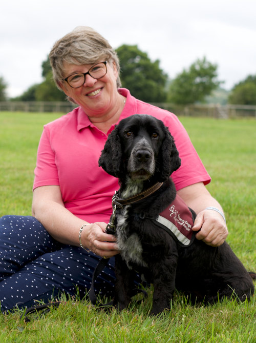 Sue and her hearing dog kristo sitting on grass
