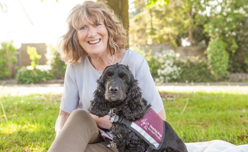 Geraldine with her Hearing Dog Bella sitting on a grassy area