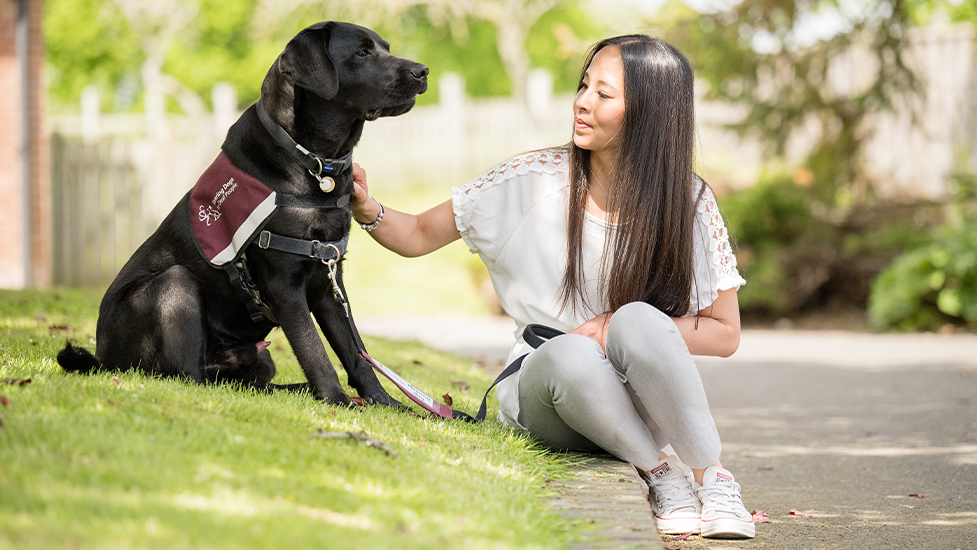 Chalky sitting outside and to the right of hearing dog Eddison and stroking him on his neck