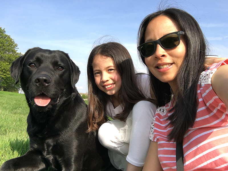 A close up of hearing dog Eddison, Chalky's daughter and Chalky all sitting together outside 