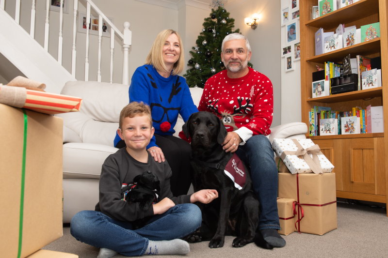 a family christmas scene with mother, father son and a black labrador