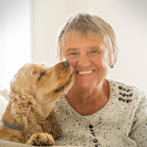 A woman smiles as a dog licks her face