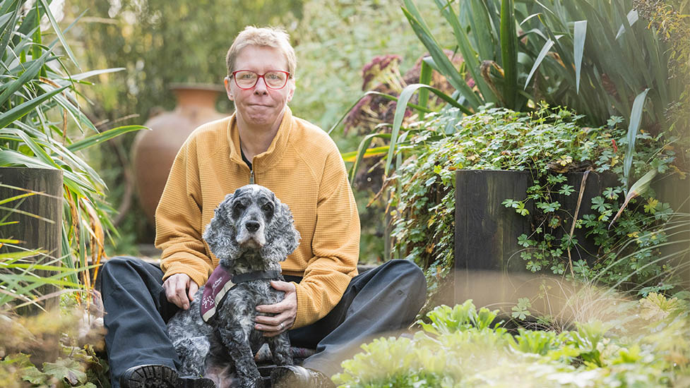 Lorna and cocker spaniel Belle are sitting next to each other in a garden