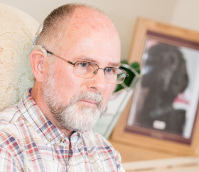 richard with a photo of his former hearing dog inthe background
