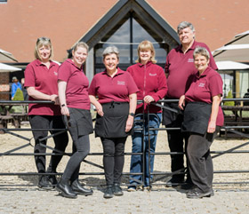 Group of people in burgundy t-shirts stood outside The Grange restaurant