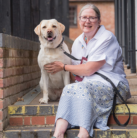 Jill and hearing dog Kit sitting next to each other outside