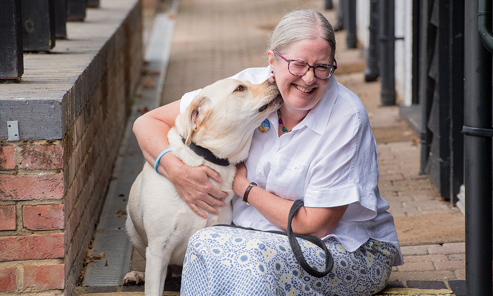 Hearing dog Kit is licking Jill's face