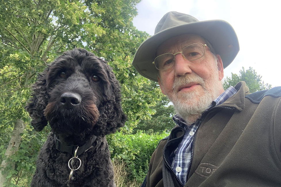 John and hearing dog cockapoo Edgar next to each other and looking straight at the camera