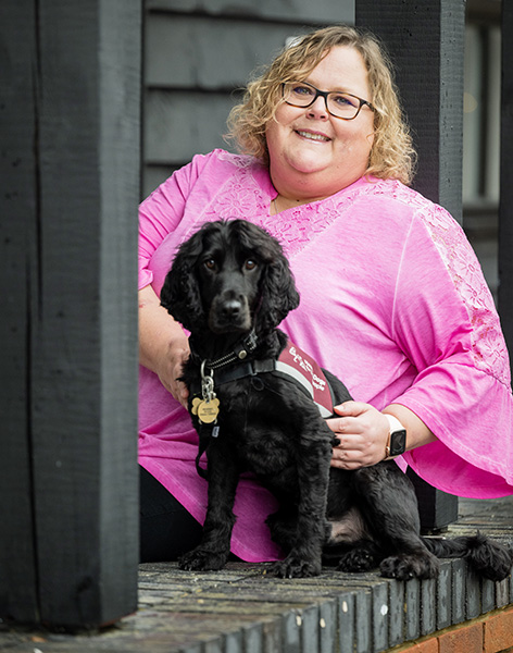 Nadine is sitting outside and is next to her hearing dog - cocker spaniel Elvis