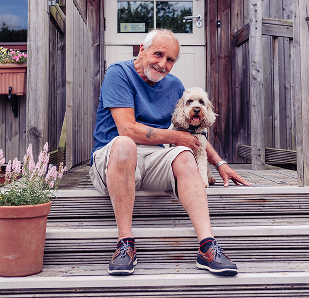 Peter and hearing dog Arya are sitting on a step outside a door