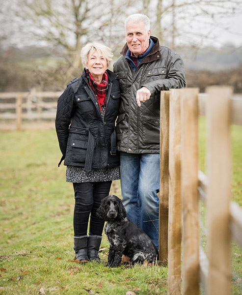 Philip and Rose are stood outside in a field with blue roan cocker spaniel Skye sitting in front of them