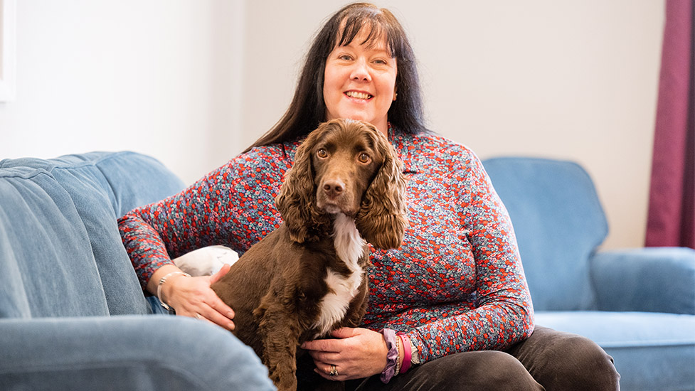 Sandra and cocker spaniel Rico are sitting on a blue sofa together. Sandra is holding Rico
