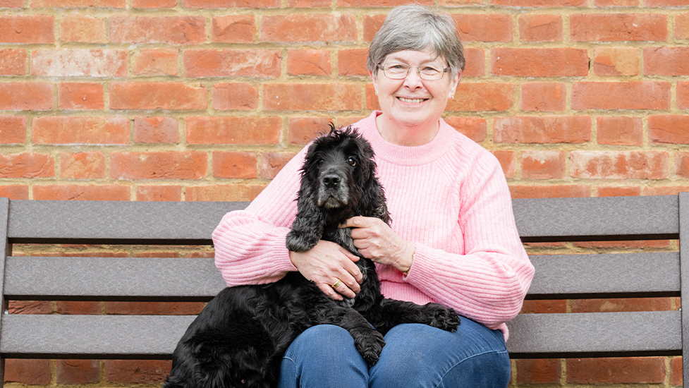 Irene is sitting on a bench with cocker spaniel Evie